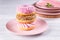 Three iced donuts are stacked on a pink ceramic plate