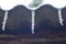 Three icicles on a slate roof under the snow