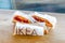 Three Ikea hot-dogs with mustard and ketchup on wooden table.