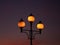 Three illuminated street lanterns during sunset, close up