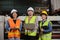 Three industrial workers use a laptop to check a paper manufacturing machine