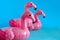 three inflatable pink flamingoes blue background copy space