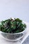 Three ingredient baked green kale chips with sea salt and olive oil, in glass bowl, vertical, copy space