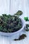 Three ingredient baked green kale chips with sea salt and olive oil, in gray bowl, vertical, copy space