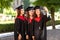 Three international graduate friends rejoicing in mantles making a selfie on a phone at University