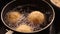 Three Italian arancini rice balls deep frying in hot boiling oil.