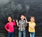Three joyful children keep imaginary balloons drawn on the blackboard