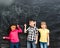 Three joyful children keep imaginary balloons drawn on the blackboard