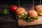 Three juicy hamburgers with meat, cheese, lettuce, tomato on a wooden Board