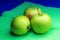 Three juicy and ripe green apples are lying on a green kitchen towel