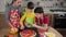 Three kids adding the olives to raw pizza