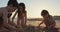 Three kids building sand castles on the beach during sunset