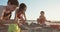 Three kids building sand castles on the beach during sunset