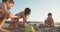 Three kids building sand castles on the beach during sunset