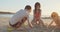 Three kids building sand castles on the beach during sunset