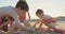 Three kids building sand castles on the beach during sunset