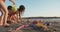 Three kids building sand castles on the beach during sunset