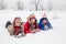 Three kids lying down together on white snow