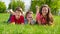 Three kids lying together on green grass meadow