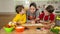 Three kids reading the cook book, making the dinner