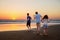 Three kids silhouettes running and jumping on beach at sunset. happy family, two school boys and one little preschool