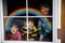 Three kids, two school kids boys and toddler girl with rainbow painted with colorful window color during pandemic