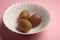 Three kiwis on bowl over pink background