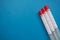 Three laboratory sample tubes with red cap on blue background