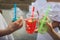 Three ladies cheering with tasty nectars with ice cubes, with black straws, palms decoration, in swim pool, transparent