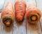 Three large carrots lie on a wooden table