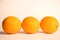 Three large oranges lie in a row on a white background