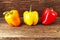 Three large peppers paprika of different colors - red, yellow and orange, on a wooden background