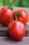 Three large red tomatoes on a wooden board. Ripe fruits of Solanum lycopersicum close-up