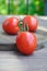 Three large red tomatoes on a wooden board. Ripe fruits of Solanum lycopersicum close-up