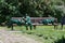 Three lazy workers sleeping on a park bench in the middle of working day. Lawn mowers stand nearby. Funny scene