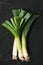 Three Leek Stalks on a Dark Gray Stone Surface