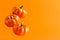 Three levitating ceramic pumpkins on orange background with copy space. Horizontal Halloween banner