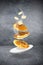 Three levitating pancakes with piece of butter and slices of bananas and white plate on gray surface