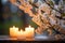 Three lit candles and white cherry blossoms on a serene stone ledge