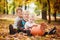 Three little brothers sitting on grass and embracing with huge pumpkin in autumn day