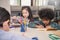 Three little children sitting hand holding pencil and coloring picture