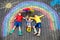 Three little children, two school kids boys and toddler girl having fun with with rainbow picture drawing with colorful