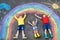 Three little children, two school kids boys and toddler girl having fun with with rainbow picture drawing with colorful