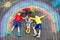 Three little children, two school kids boys and toddler girl having fun with with rainbow picture drawing with colorful