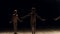 Three little girls dancers dance ballet on stage on a black background.