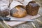 Three loaves of bread on a board with a knife, whole grain bread