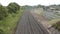 three long railroad tracks with bend curve next to grass trees and dirt with sky