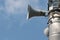 Three loudspeakers on pole against blue sky