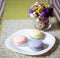 Three macaron on the plate near a vase