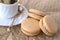 Three macaroni cake and a cup of coffee on a beige polka dot background. Top view